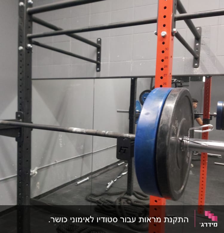 מראה גדולה משקפת חדר כושר עם משקולות